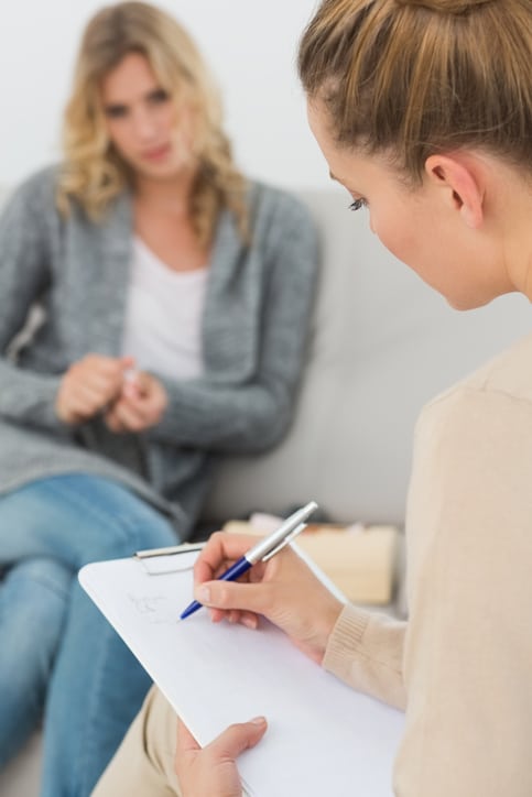 Therapist writing notes on her clipboard